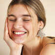 Model smiling with hand under chin wearing My Doris Silver Beaded Butterfly Drop Earrings