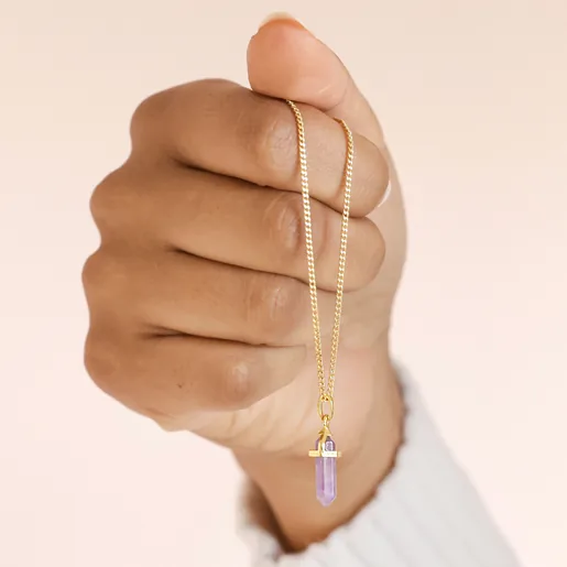 Model holding the Amethyst Crystal Point Pendant Necklace in Gold in fist