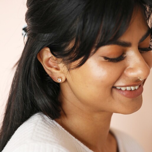 Brunette model smiling wearing Festive Crystal Reindeer Stud Earrings in Gold