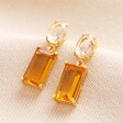 A pair of drop earrings with a clear oval crystal atop a rectangular amber gemstone 