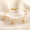 Ball and Star Paperclip Chain Bracelet in Gold on Beige Background