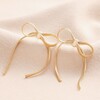 Bow Snake Chain Statement Stud Earrings in Gold on Beige Fabric