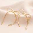 Bow Snake Chain Statement Stud Earrings in Gold on Beige Fabric