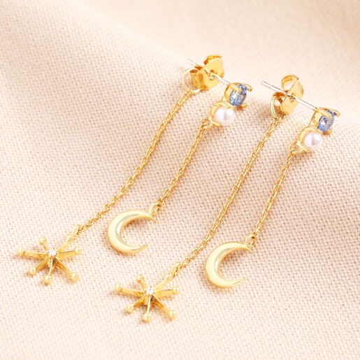 Blue Crystal Celestial Drop Earrings in Gold on a Beige Background.