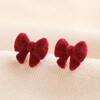 Red Velvet Bow Stud Earrings Against Beige Background 