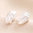 Twist Knot Stud Earrings in Silver against Beige Background