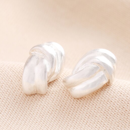 Twist Knot Stud Earrings in Silver Twist Knot Stud Earrings in Silver against Beige Background