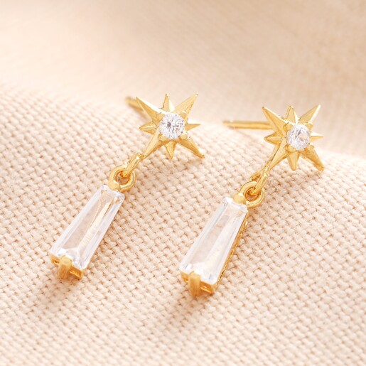 Star and Crystal Drop Earrings Star and Crystal Drop Earrings in Gold Against Beige Background
