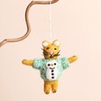 A cat hanging decorating win yellow with a blue sweater with a snowman design