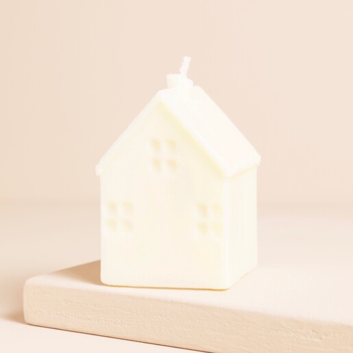 A cottage shaped candle with the wick in the chimney