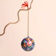 A blue floral bauble with a gold rope and red tassel