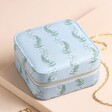 A Dusky Blue Soft Jewellery Box with a Foliage Print Resting on a Neutral Surface