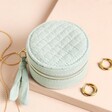 Quilted Round Mini Travel Jewellery Case closed and ripped up against a beige background