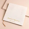 Personalised wedding guest book with custom gold cursive font on a beige background