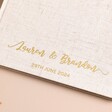 Close up of personalised wedding guest book with custom gold cursive font 