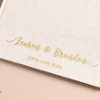 Close up of personalised wedding guest book with custom gold cursive font 