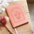 Pink Vegan Leather Embossed Notebook on side table with a pen