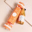 Passion Fruit Martini Christmas Cracker on beige background with bottle beside packaging