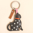 Caroline Gardner Black Cat Heart Keyring with White Hearts, Red Collar and Pink Strap on a Beige Background