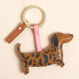 A sausage dog keyring covered in leopard print vegan leather, attached to keyring loop by strip of pink vegan leather