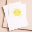 A white card with a smiling sun in the centre