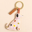 A Labrador dog keyring covered in off white vegan leather, attached to a gold keyring loop by strip of brown vegan leather