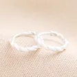 Sterling Silver Rope Huggie Hoop Earrings on Beige Background