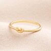 A gold thin band ring with a knot effect at the front