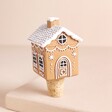 A Beige Resin House Shaped Ornament Attached to a Cork Stopper on a Neutral Background