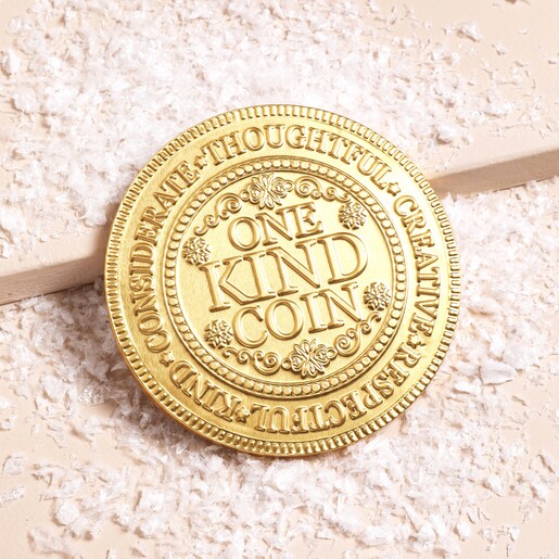 Front of the coin Front of The Chocolate Gift Company Kindness Milk Chocolate Coin against snowy backgrounf