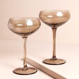 A set of two brown glasses on a Beige Background