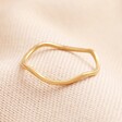 Stainless Steel Thin Band Wave Ring in Gold on a Beige Background