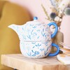 A blue debossed floral teapot that sits neatly on a teacup