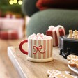 A Stripy Cream Green and Red Mug With a Red Handle Filled With Hot Chocolate and Marshmallows