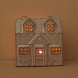 Mini Rustic House Tealight Holder in a dimly lit backdrop, displaying glow from internal candle