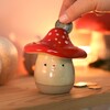 A squat toadstool shaped money box with a slit for your coins on the lid and the accessible point on the underside