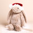 Jellycat Bashful Bunny Decoration Soft Toy with a santa hat on a beige background