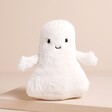 A Soft Cuddly Ghost Toy With Cream Fur and a Smiling Face Sitting on Neutral Background