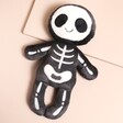 A skeleton soft toy with a black background and mixed fabrics