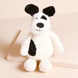 Jellycat Small Bashful Black & Cream Puppy Soft Toy Against Beige Background