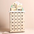 A 24 door advent calendar with a cutout gingerbread village scene across the top, personalised with your choice of name