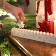 A wooden countdown shaped like a village with festive engravings and a pointed star tracker connected by a string