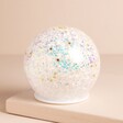 Iridescent LED Glitter Light Globe on a Beige Background.