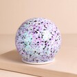 Iridescent LED Moonrise Glitter Light Globe on a Beige Background.