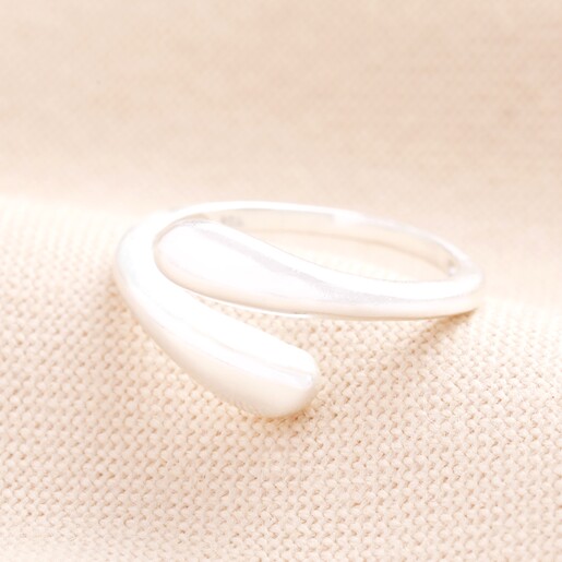 Adjustable Sterling Silver Teardrop Wrap Ring in Silver on a Beige Background.