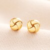 Sterling Silver Knot Stud Earrings in Gold on Beige Background