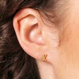 Model Shot of Sterling Silver Turtle Stud Earrings in Gold on Beige Background