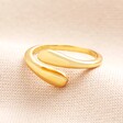 Adjustable Sterling Silver Teardrop Wrap Ring in Gold on a Beige Background.