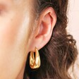 Close Up of Tapered Oval Hoop Earrings in Gold on Model