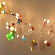 Illuminated Battery Powered Folklore Colourful Charm Wire String Lights Against Wall